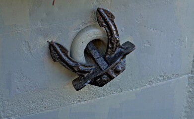 Black iron anchor secured on an old white boat.