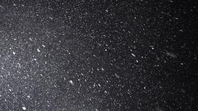 A dense heavy blizzard snowstorm VFX insert in slow-motion on a black screen. Black screen Christmas snowstorm. Particles swirling moved by wind. Snow is moving through space. Snowstorm on black.