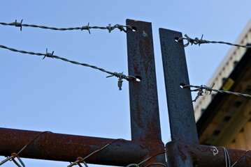 Rusted gate topped with barbed wire.