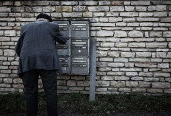 homme de dos devant sa boîte aux lettres: la relève du courrier