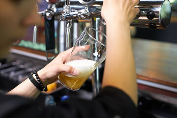 close up of cropped bartender pouring beer while standing at the bar counter. have rest, celebraton, leisure, drinking and beverage concept