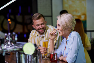 the girl likes the jokes of a stranger, caucasian guy flirt with blond girl in a pub or bar
