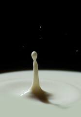 Milk dancer with waves around her drop of milk falling on more milk