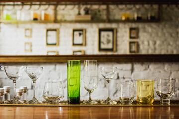 Different kinds of glasses on a bar counter, rocks, old fashioned, highball, nick and nora, coupe