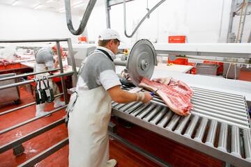 A group of worker in meat factory, chopped a fresh beef meat in pieces on work, industry food.