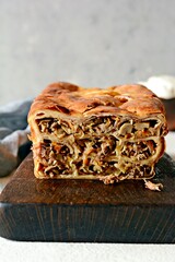 Pancake pie with meat and mushrooms on a gray background. Pancake cake in the form of bread. Slavic cuisine. Pancake pie with meat and mushrooms on a gray background, copy space. Shrovetide Maslenitsa