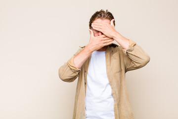 blonde adult caucasic man covering face with both hands saying no to the camera! refusing pictures...