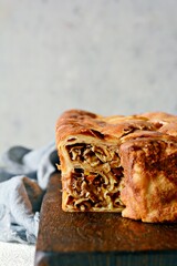 Pancake pie with meat and mushrooms on a gray background. Pancake cake in the form of bread. Slavic cuisine. Pancake pie with meat and mushrooms on a gray background, copy space. Shrovetide Maslenitsa