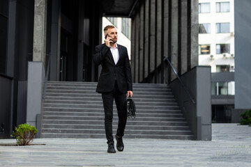 A young man in strict clothes with a bag in his hands goes down