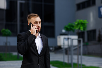 Young businessman goes to work, talking on a cell phone on the street