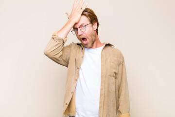 blonde adult caucasic man raising palm to forehead thinking oops, after making a stupid mistake or...