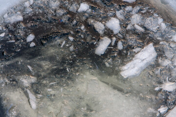 Water with ice in the hole on the frozen river