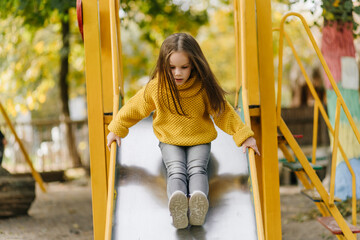 Adorable kid spending leisure time at playground. Outdoor shot of carefree preteen girl in yellow...