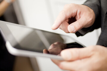 電車でタブレットPCを見るビジネスマン