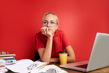 portrait of confident caucasian blonde female sitting at office desk with laptop and papers, young...