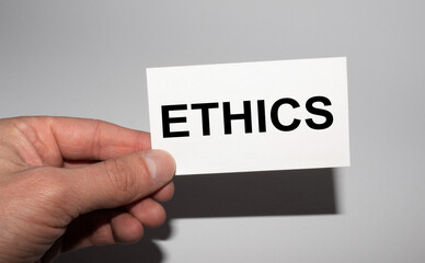 Message on the card ETHICS, in hands of businessman.