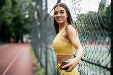 Beautiful woman training on running track. Young woman in yellow sportswear...