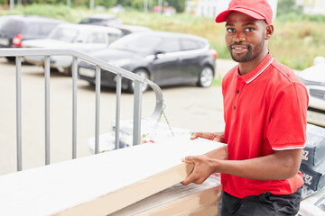 young african black man work in delivery company, came to clients to give it, wearing red uniform