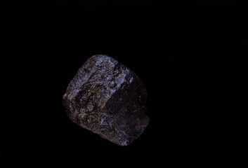 .super macro shot single crystal black hawaiian salt very close on black background isolated