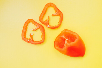 Bright orange sliced bell pepper fruits on a colored background. View from above. Flat layer. Yellow background.
