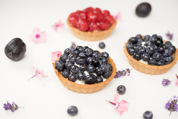 Delicious fresh dessert baskets of shortbread decorated with fresh blueberries and raspberries among the flowers. The concept of baking bakery, sweet food. Close-up photo