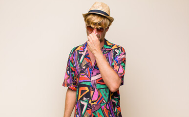 blonde adult traveller manfeeling disgusted, holding nose to avoid smelling a foul and unpleasant...