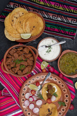 Soft corn street tacos with vegetarian filling consisting of seitan, mushrooms, carrot, chile verde and cream in traditional Mexican table setting