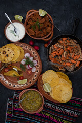 Soft corn street tacos with vegetarian filling consisting of seitan, mushrooms, carrot, chile verde and cream in traditional Mexican table setting