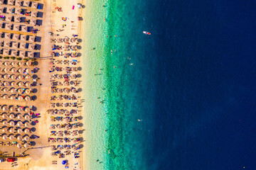 Fototapeta na wymiar Concept of summer vacation. View from above, stunning aerial view of an amazing beach with beach umbrellas and turquoise clear water. Top view on a sun lounger under an umbrella on the sandy beach