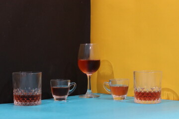 Red wine poured in wine glass and other glasses on a colourful table. Different glasses of wine with colourful background