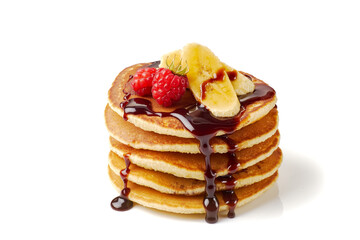 Stack of pancakes with banana,raspberries and chocolate syrup on white