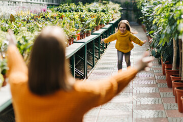 Positive kid running to mother and smiling. Happy young woman playing with daughter.
