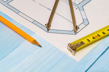 House diagrams and accessories for drawing lying on construction drawing and a blue workshop table...