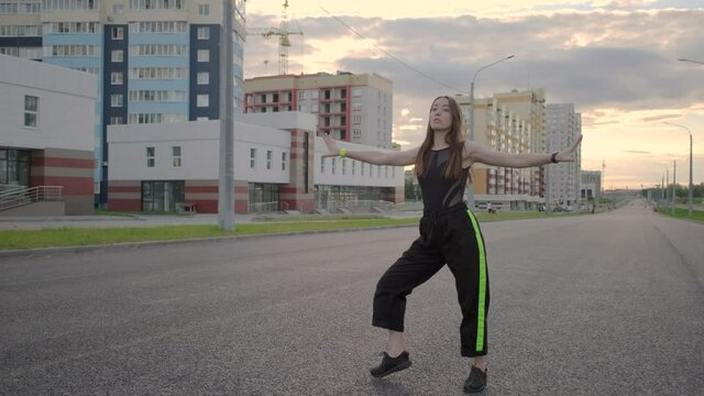 young beautiful woman dancing on a wide city street. Summer evening. Sunny sunset. Hip hop. Contemporary choreography. Slow motion. Gimbal shot