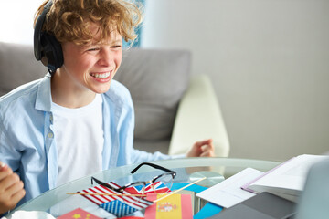 caucasian teen boy sit with laptop, studying online, enjoy education during quarantine. indoors