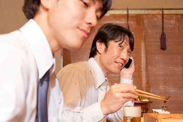料理を食べながら電話するビジネスマン
