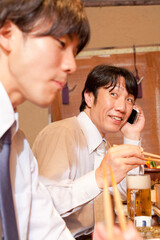 料理を食べながら電話するビジネスマン