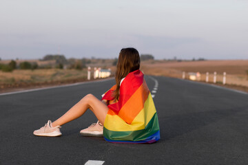 Girl looking at the view, holding a rainbow flag