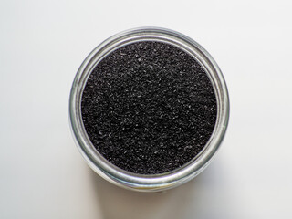 Activated charcoal powder for cosmetic face mask in a jar top view with copy space, white background