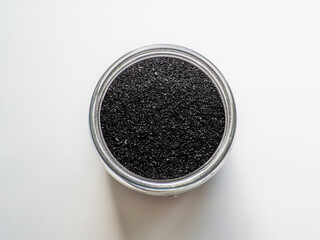 Activated charcoal powder for cosmetic face mask in a jar top view with copy space, white background