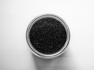 Activated charcoal powder for cosmetic face masks in a jar top view with copy space, white background