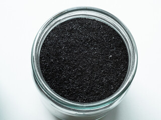 Activated carbon powder for cosmetic face mask in one glass jars, top view on white back