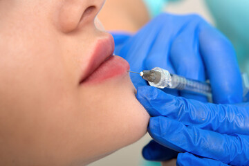 cosmetologist making injection in face, lips.