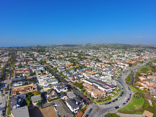 breathtaking aerial shot of the homes, streets and cars in the city skyline with a blue sky at...