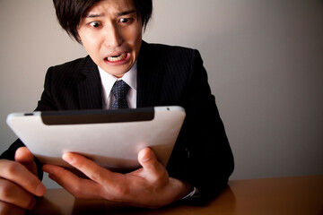 タブレットＰＣを見て驚くビジネスマン