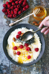 Selective focus. Breakfast bowl with raspberries, honey and seeds.