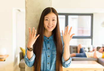 young pretty asian woman smiling and looking friendly, showing number nine or ninth with hand...
