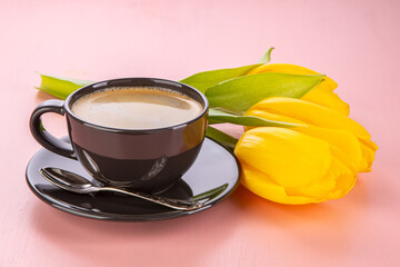 Spring still life on a pink background. Tulips and a cup of coffee.