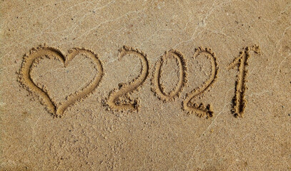 The concept of a New year. Heart and numbers 2021 in the sand. Summer beach holidays . The message is handwritten