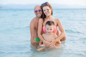 Fototapeta na wymiar Happy family on the beach, blue ocean background.